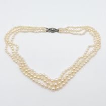 A triple row of graduated Cultured Pearls on lozenge shaped clasp stamped sterling silver, set