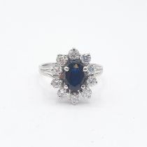 A Sapphire and Diamond Cluster Ring claw-set oval-cut sapphire within a frame of ten brilliant-cut