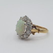 An Opal and Diamond Cluster Ring claw-set oval opal cabochon within frame of ten brilliant-cut