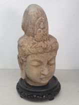 A carved stone Buddha Head with later carved wooden associated Stand. A/F. (Head alone measures 11"