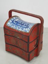 A Chinese three tier lacquered Tiffin Carrier, the lid with inset blue and white tile, with red