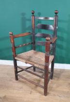 An 18th Century primitive Elbow Chair with ladder back, rush seat on turned supports & stretchers.