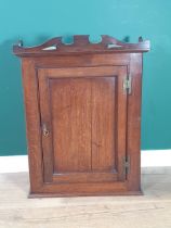 An 18th Century oak hanging Cupboard with shaped surmount, fitted single panelled door enclosing