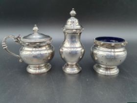 An Elizabeth II silver three piece circular Condiment Set with celtic style friezes, Birmingham 1956