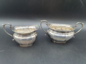 A George V silver two handled Sugar Bowl and Milk Jug of panelled oval form, Birmingham 1926/7,