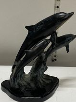 A bronzed metal sculpture of three dolphins