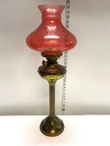 A antique oil lamp with brass column and Cranberry shade h67cm, shipping unavailable