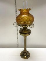 A antique brass based oil lamp with amber glass shade h70cm, shipping unavailable
