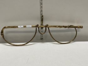 A unusual heavy brass wall mounted hanging rack in the form of a riding crop