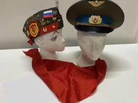 Two Russian military caps one with a selection of badges