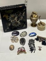 A papier mache box and contents of costume brooches and two vintage table lighters