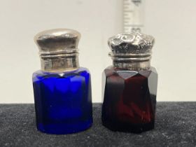 Two small hallmarked silver topped scent bottles, one in blue glass and one in cranberry glass