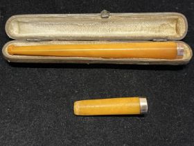 A cased hallmarked long cigarette holder with 9ct mount and butterscotch amber mouth piece in