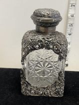 A hallmarked for London 1905 large silver topped scent bottle with scrolling foliage top and bottom,