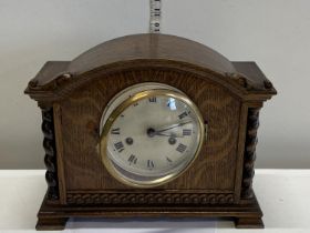 A wooden cased mantle clock with key and pendulum