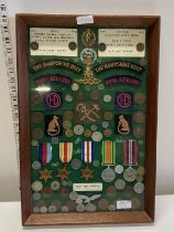 A framed unique collection of medals, cap badges and shoulder flashes and other belonging to a
