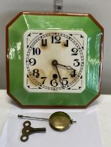 An art deco period ceramic faced wall clock with pendulum and key