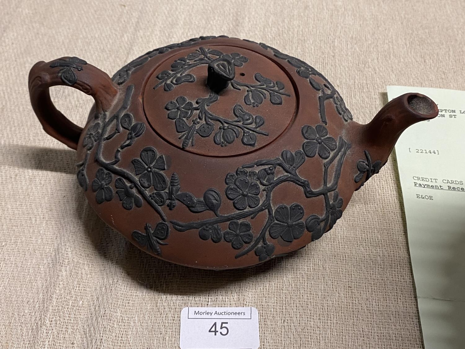A antique terracotta teapot with applied flower decoration