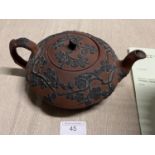 A antique terracotta teapot with applied flower decoration