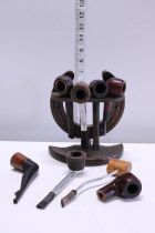 A vintage wooden pipe rack and selection of assorted pipes