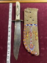 An original Bowie knife with a bone handle in a native American Indian style sheath. Blade length