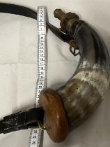 A vintage black powder horn and strap stamped Sykes to the brass top