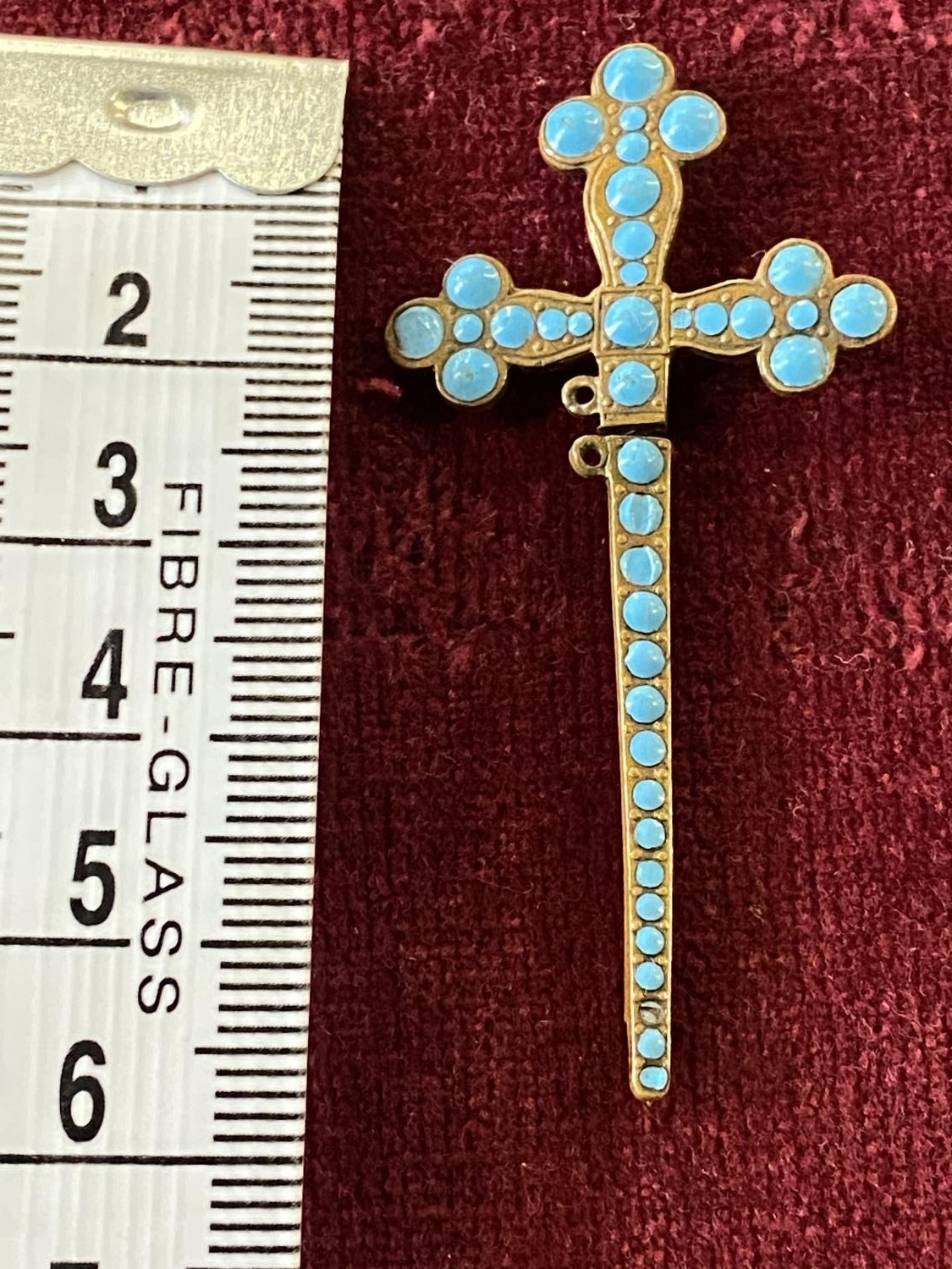 A stick pin in the form of a crucifix with turquoise decoration