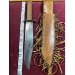 An original Bowie knife in a leather sheath. Blade stamped Sussex Armoury. Blade length 25cm over