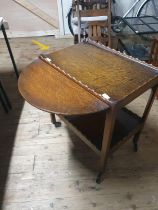 A antique tea trolley with drop leave sides on castors, shipping unavailable