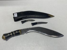 A vintage Kukri knife with two smaller knives in leather scabbard