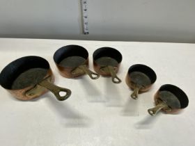 Five antique small graduated copper and brass saucepans