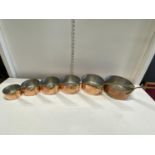 Six antique graduated copper and brass saucepans