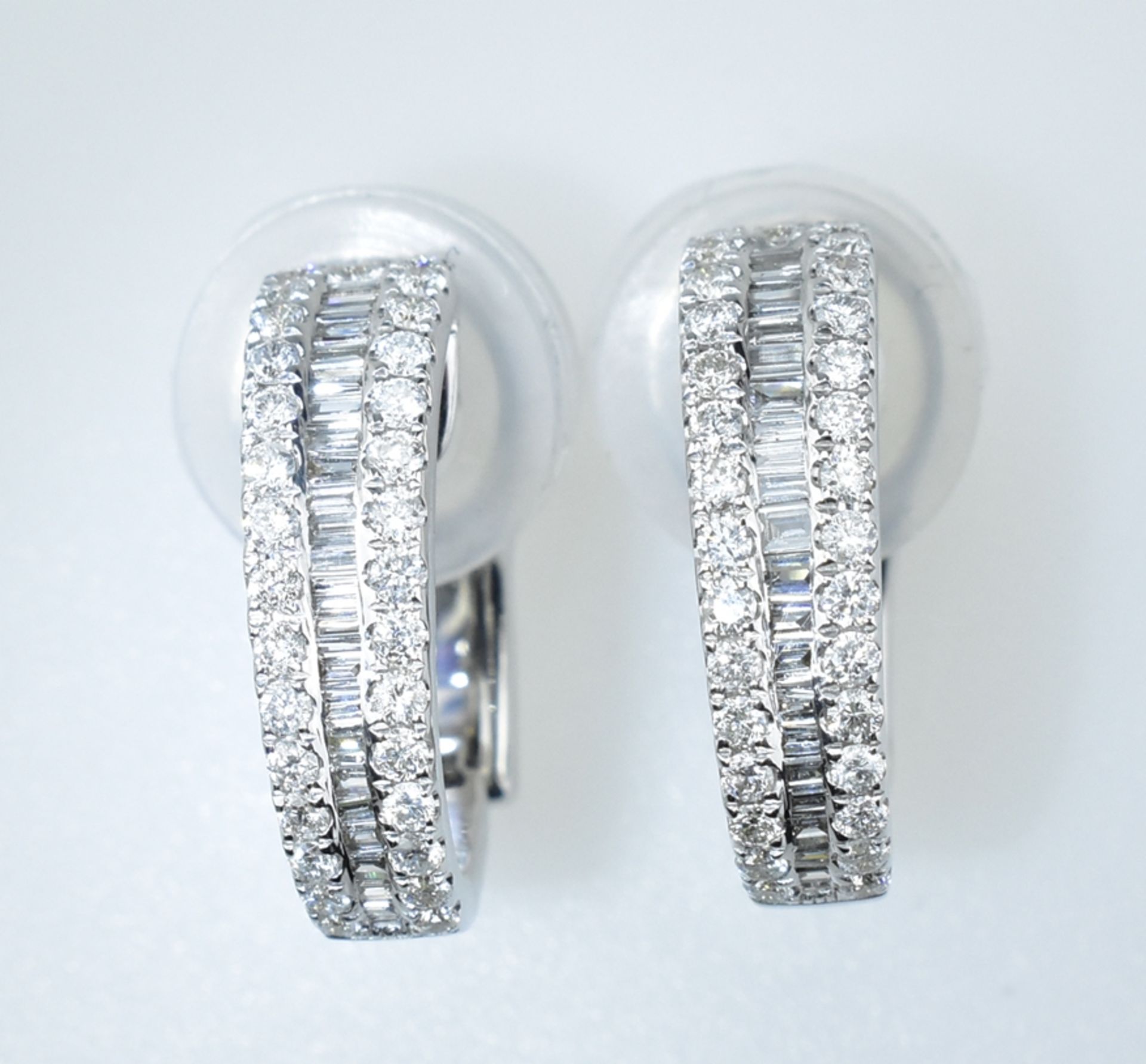 Paar Brillant-Halbcreolen.  Mit 1,08 ct. Brillanten und Baguetten. 18 ct. WG. Klapp-Steckbrisur