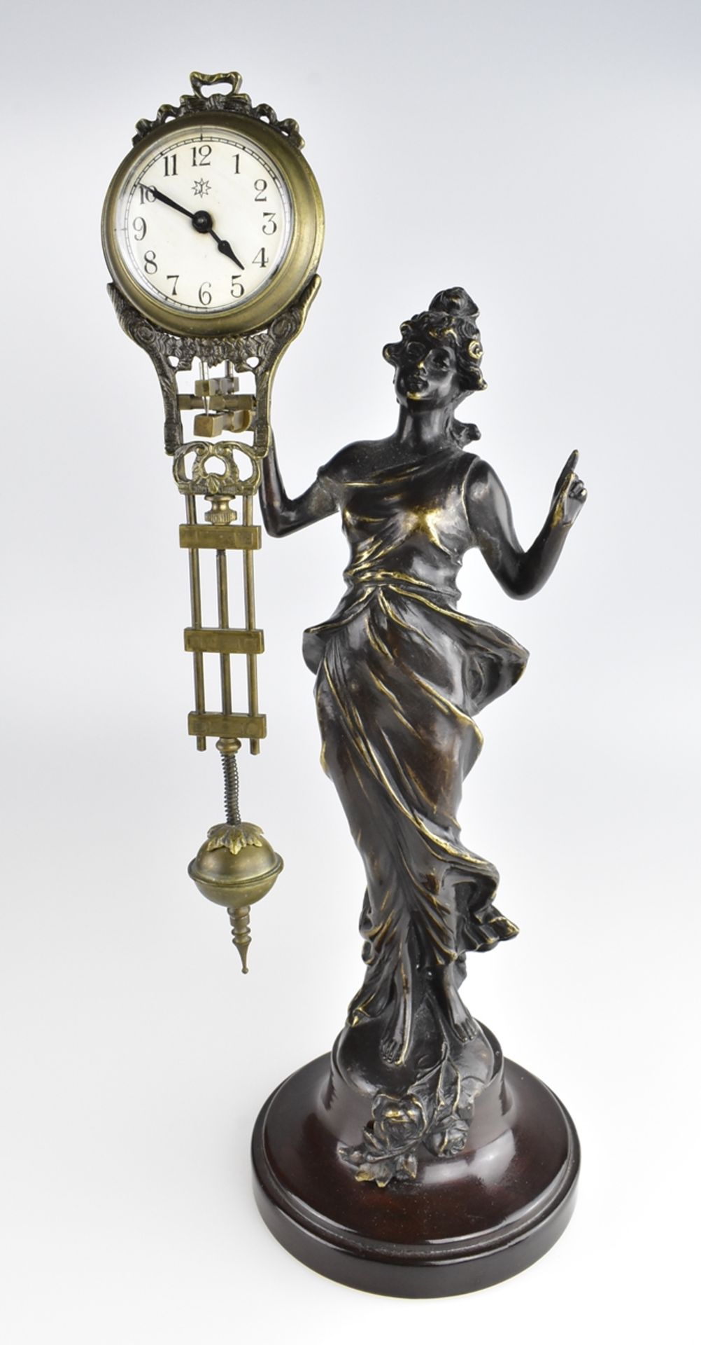 Tischuhr, sog. Mysterieuse. Leicht gewandete Edeldame mit erhobenem Zeigefinger (Bronze) auf Holzs