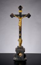Standkruzifix. Holz und Messing. Im Sockel Schublade mit Reliquie. Apostelfigur zu Füßen des Kreuze