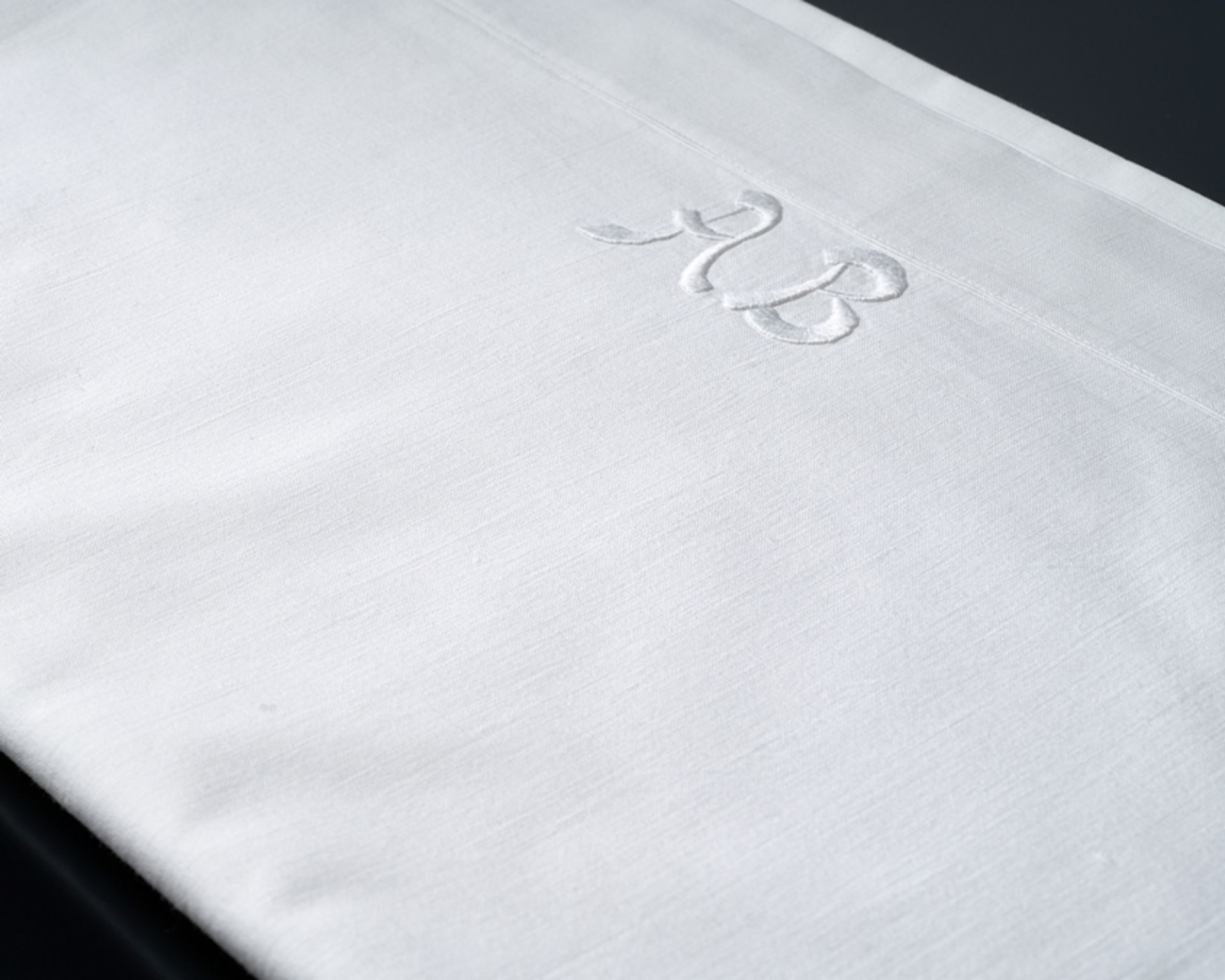 Großes glattes Tuch mit Monogramm A B. Feine glatte Baumwolle. An einem Schmalrand zwei große relie