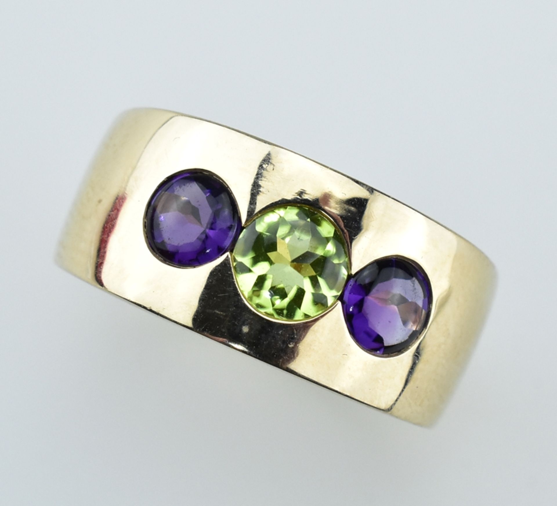 Breiter Bandring. Mittig facettierter Peridot flankiert von zwei Amethysten zus. 1,32 ct. 14 ct. R