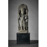 Stehender Surya als Stele.  Der Sonnengott mit reichem Kopfschmuck. In den erhobenen Händen zwei Bl