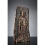Kleine Stele eines stehenden Bodhisattva Chuan Yin. Auf Plinthensockel vor Wandhintergrund stehend
