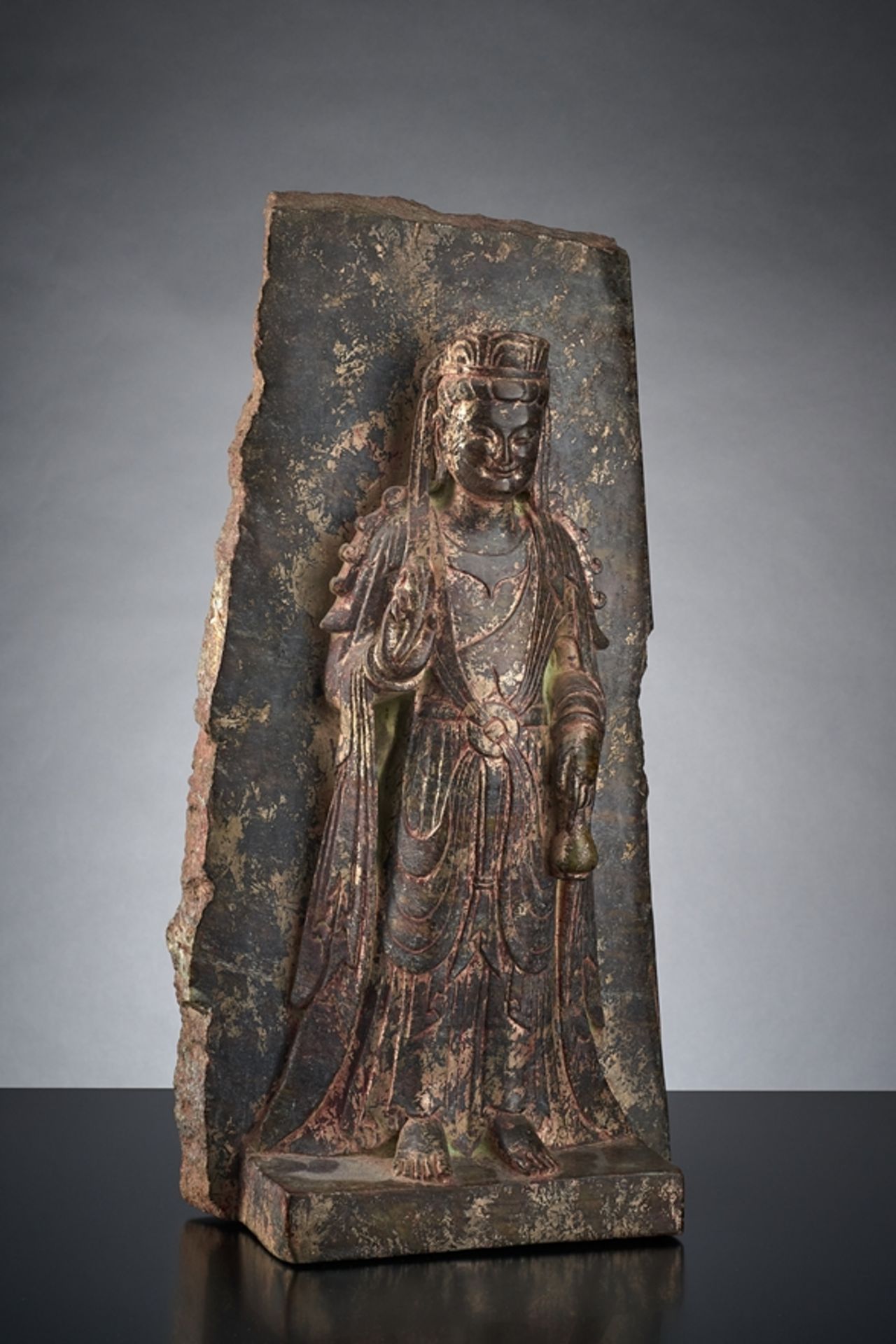 Kleine Stele eines stehenden Bodhisattva Chuan Yin. Auf Plinthensockel vor Wandhintergrund stehend