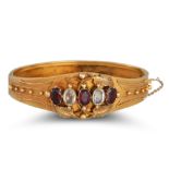 AN ANTIQUE GARNET AND WHITE GEMSTONE BANGLE, in yellow gold, Etruscan style decoration ** testing as