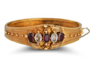 AN ANTIQUE GARNET AND WHITE GEMSTONE BANGLE, in yellow gold, Etruscan style decoration ** testing as