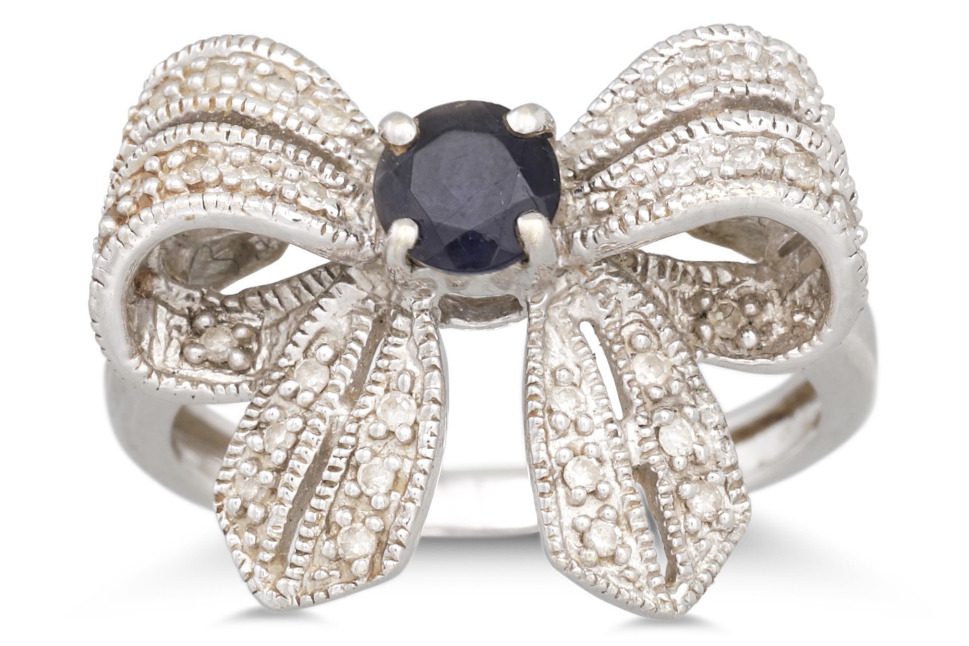 A DIAMOND AND GEM SET RING, modelled as a bow, mounted in white gold. Size: N - O