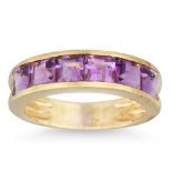 AN AMETHYST BAND RING, the six channel set French cut amethysts mounted in yellow gold, size K
