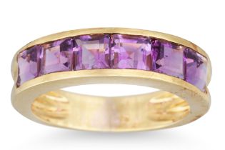 AN AMETHYST BAND RING, the six channel set French cut amethysts mounted in yellow gold, size K