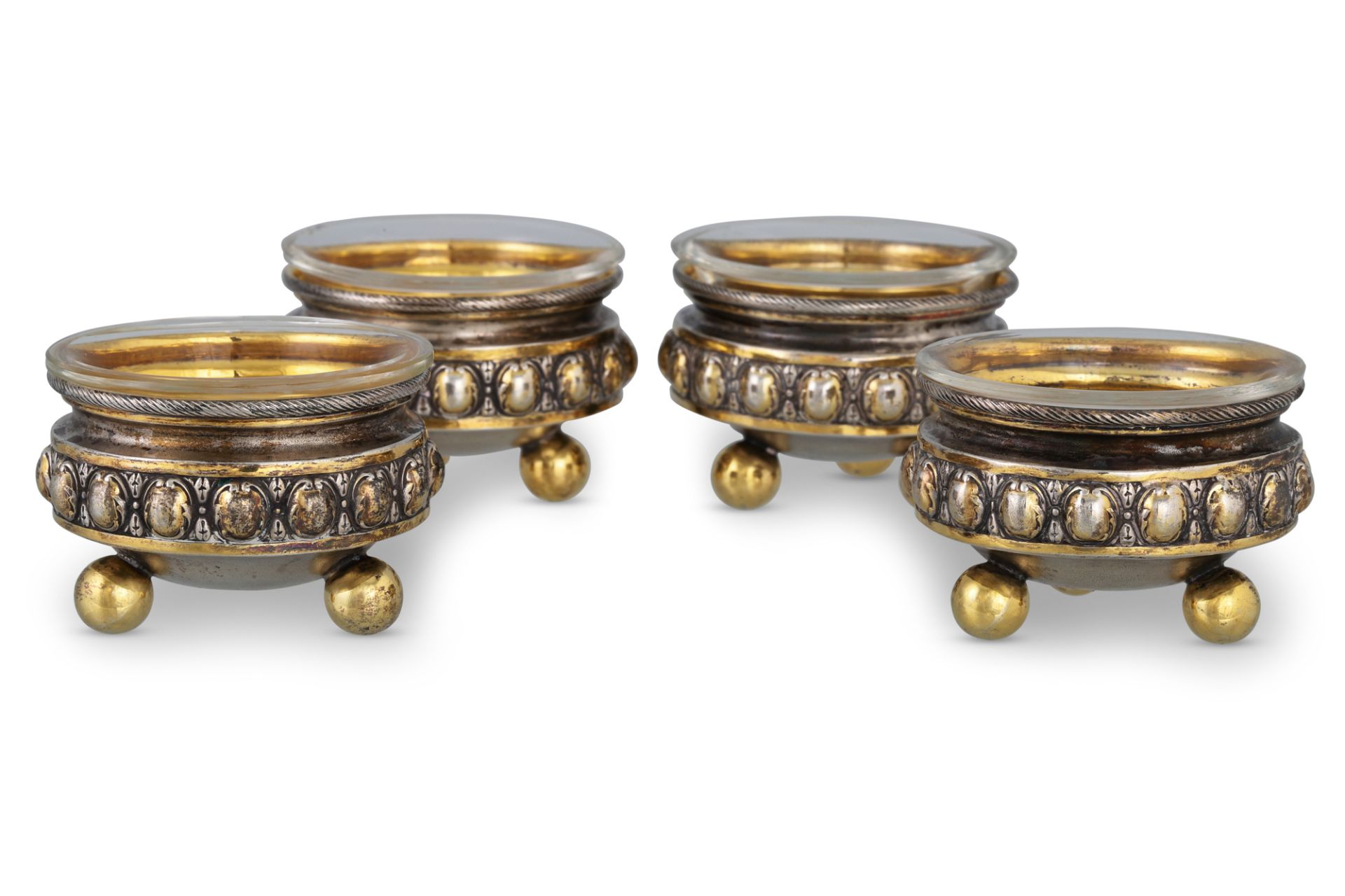 A SET OF FOUR GERMAN (.800 silver) gilt circular salt cellars, with clear glass liners, raised