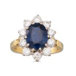 A SAPPHIRE AND DIAMOND CLUSTER RING, the oval sapphire to a brilliant cut diamond surround,