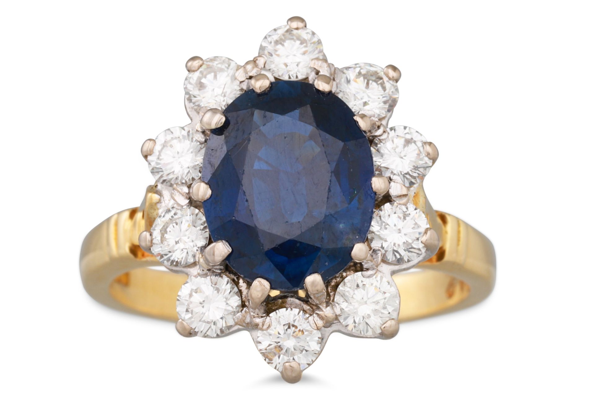 A SAPPHIRE AND DIAMOND CLUSTER RING, the oval sapphire to a brilliant cut diamond surround,