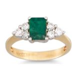 AN EMERALD AND DIAMOND THREE STONE RING, the rectangular emerald to diamond trio sides, mounted in