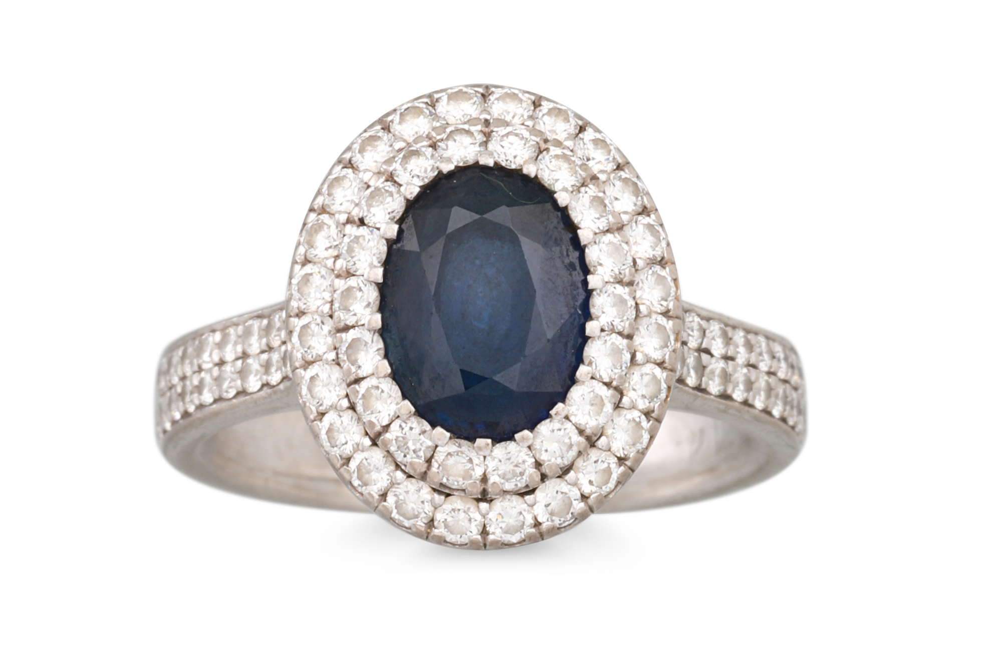 A SAPPHIRE AND DIAMOND CLUSTER RING, the oval sapphire to a two rowed diamond halo surround, to